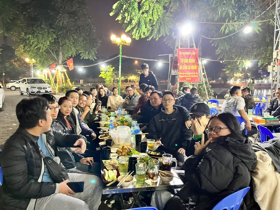 Đội VNTAY liên hoan ngoài trời buổi tối, bàn dài đông người và nhiều món ăn Đội VNTAY liên hoan ngoài trời buổi tối, bàn dài đông người và nhiều món ăn