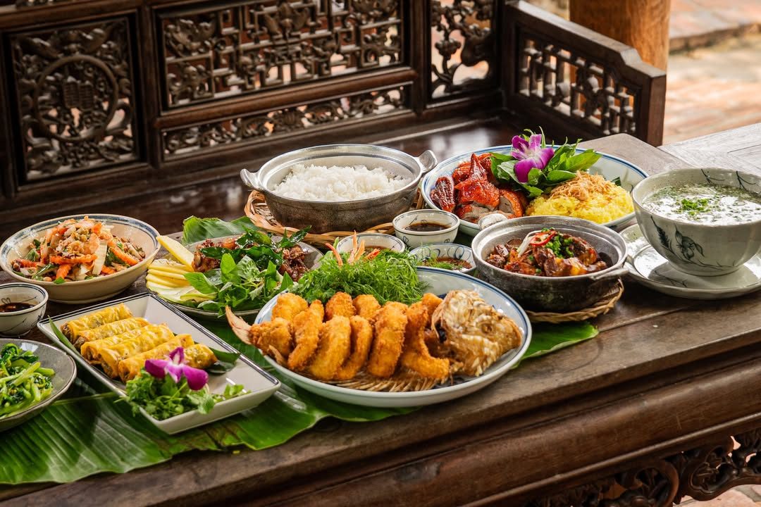 Mâm cơm Việt nhiều món bày trên sập gỗ chạm khắc tại Nhà hàng Bến Bạc