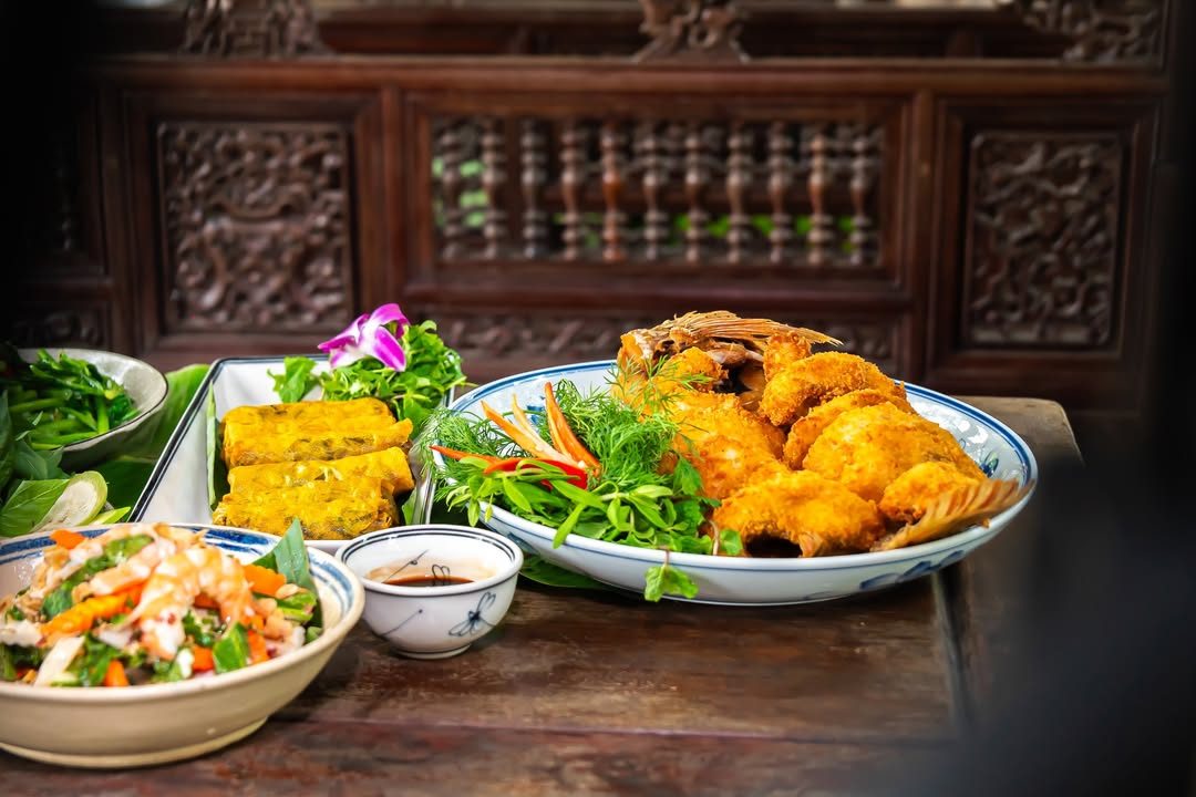 Cá chiên giòn, chả trứng và nộm rau bày trên bàn gỗ tại Nhà hàng Bến Bạc