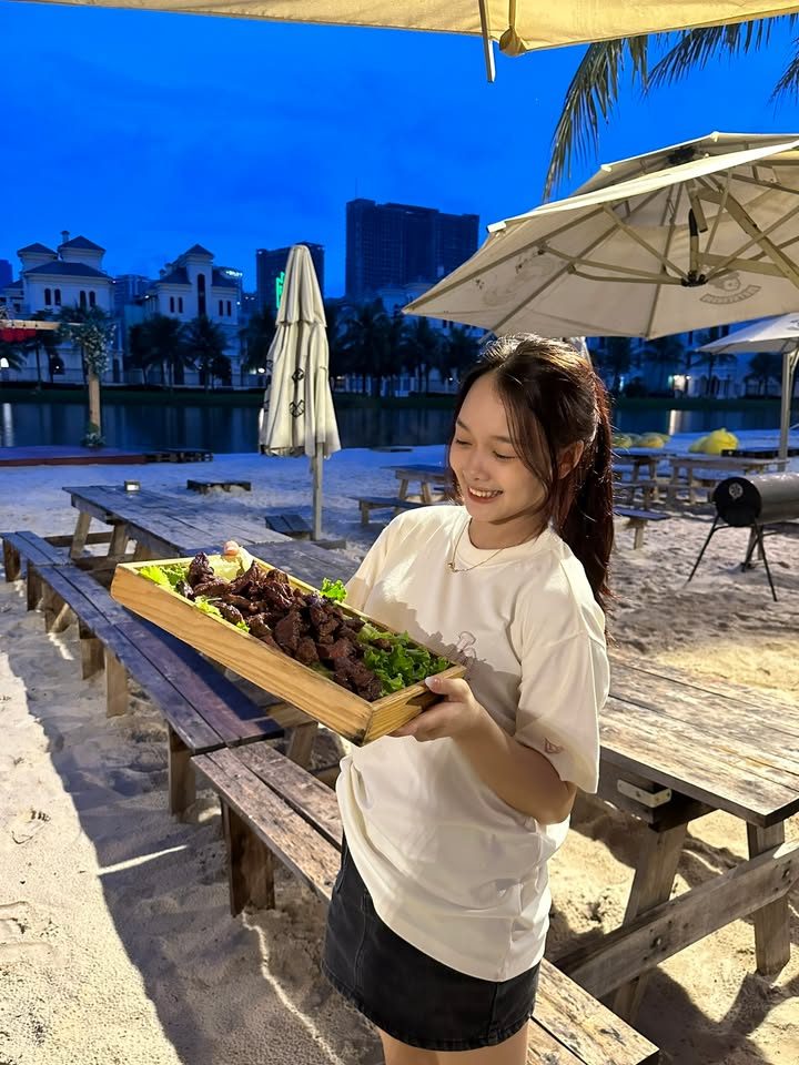 Cô gái bưng khay đồ nướng trên bãi cát ven hồ trong buổi chụp ngoài trời Cô gái bưng khay đồ nướng trên bãi cát ven hồ trong buổi chụp ngoài trời